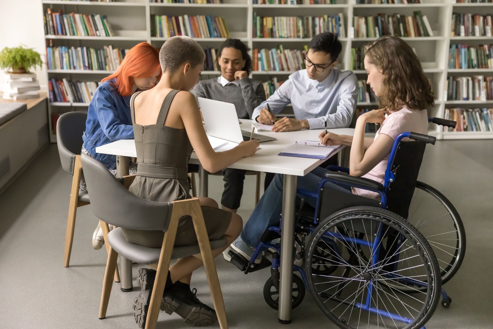 Students inclusively college mate with disability sitting at table